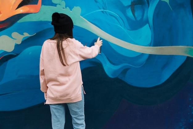 Hintere ansicht von frauenhandzeichnungsgraffiti mit sprühfarbe Kostenlose Fotos