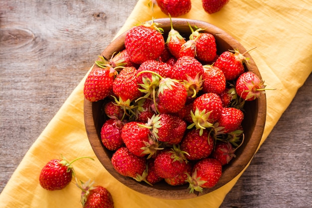 Hölzerne platte mit erdbeeren auf einer serviette auf dem tisch. ansicht von oben Premium Fotos