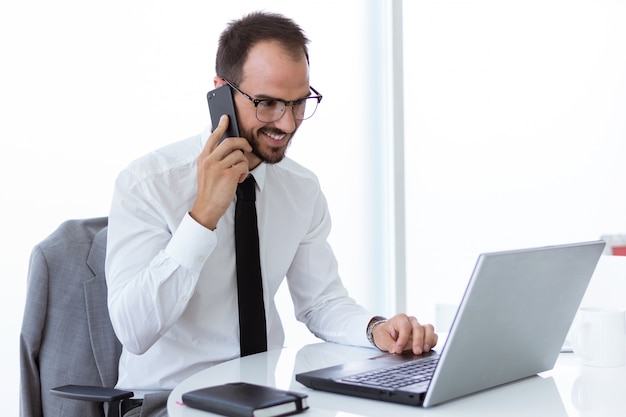 Hübscher Junger Mann Der Mit Laptop Und Handy Im Büro Arbeitet Download Der Kostenlosen Fotos