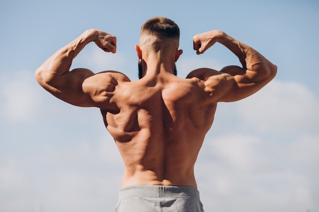 Hubscher Bartiger Bodybuilder Mann Mit Perfektem Muskelkorper Der Draussen Auf Dem Himmelhintergrund Aufwirft Starker Mann Mit Nacktem Oberkorper Der Wegschaut Blick Von Hinten Premium Foto