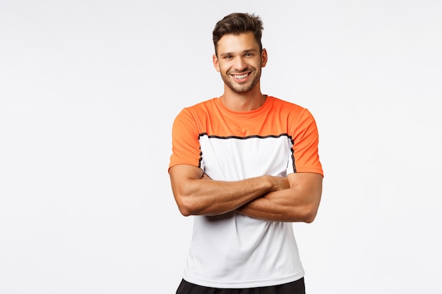 Hübscher lächelnder mannbodybuilder, kreuzarme über kasten, abnutzungssportt-shirt. Premium Fotos