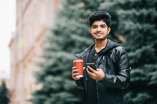 Kostenlos Foto Hubscher Mann Student Mit Brillen Die Mit Freunden Auf Handy Sprechen Die Stadtischen Kaffee Geniessen Wahrend Auf Strasse Gehen