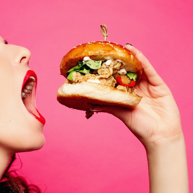 Hungrige frau mit geöffnetem mund großen hamburger essend. Premium Fotos