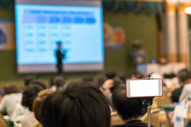 Intelligentes mobiltelefon, das live-streaming zu asiatischem sprecher mit beiläufigem anzug auf der bühne vor tut Premium Fotos