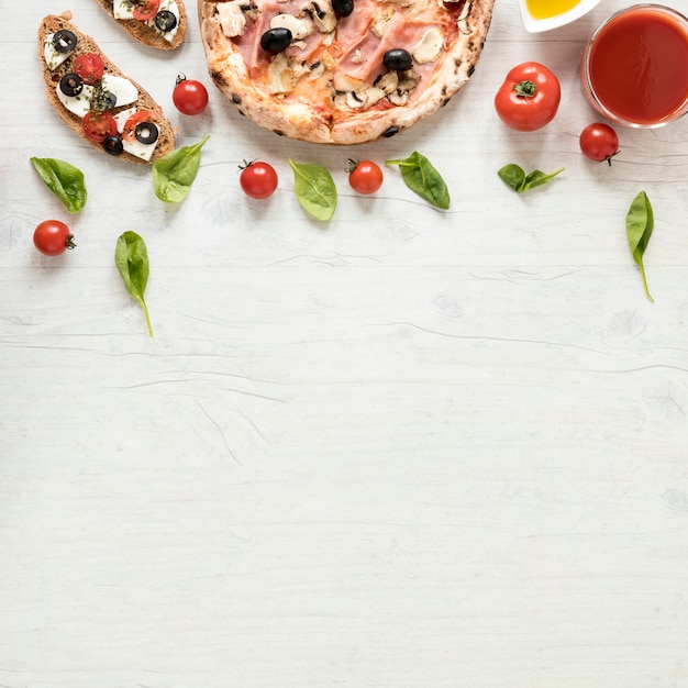 Italienische pizza und bruschetta mit bestandteil über hölzernem strukturiertem hintergrund Kostenlose Fotos