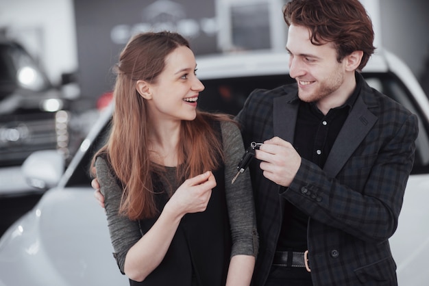 Jetzt wird ihr traum wahr. autoverkäufer, der den jungen attraktiven inhabern den schlüssel des neuen autos gibt Premium Fotos