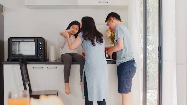 Junge asiatische japanische familie, die zu hause kocht. glückliche mutter, vati und tochter des lebensstils, die zusammen teigwaren und spaghettis zum frühstücksmahlzeit in der modernen küche am haus morgens macht. Kostenlose Fotos