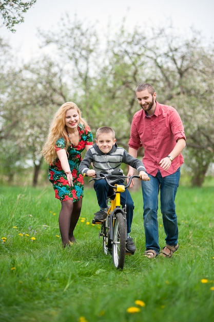 Junge eltern, die seinem sohn beibringen, fahrrad zu