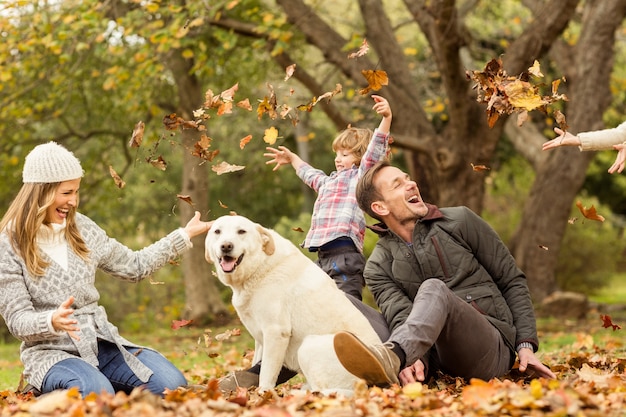 Junge familie mit einem hund in den blättern PremiumFoto