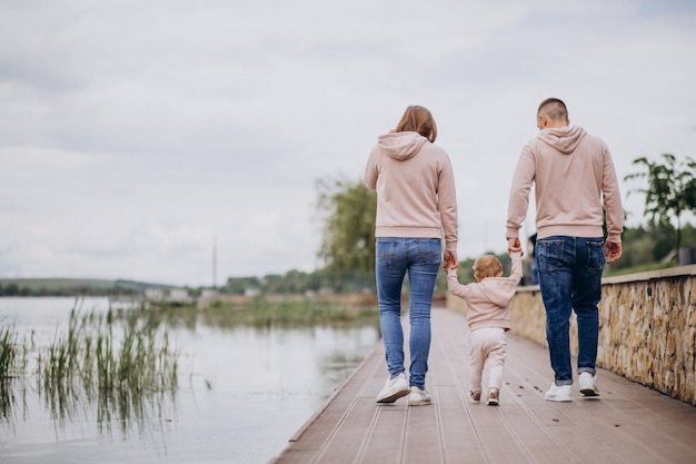 Junge familie mit ihrem kleinen baby kind im park am see Kostenlose Fotos