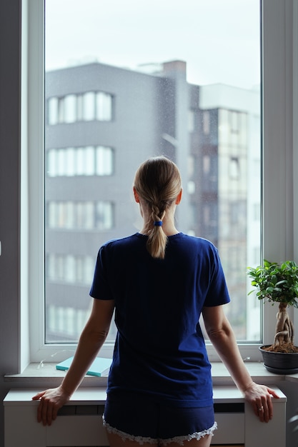 Junge frau, die durch fenster auf die stadt schaut