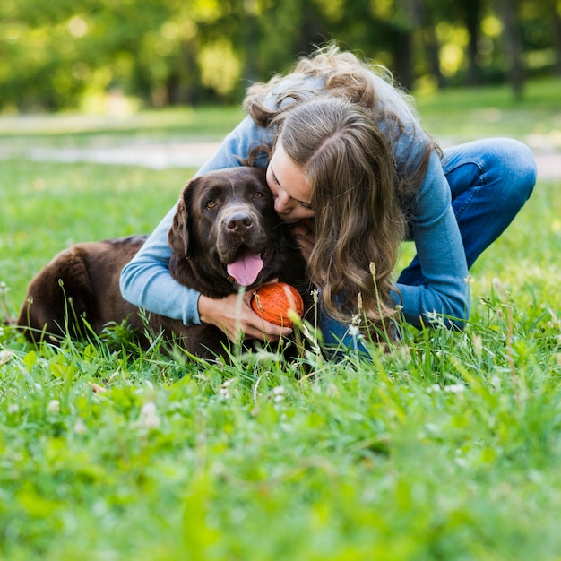 Junge frau, die ihren hund im park küsst Kostenlose Foto