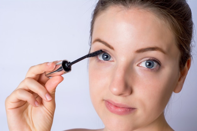Junge frau, die schwarze wimperntusche anwendet. Premium Fotos