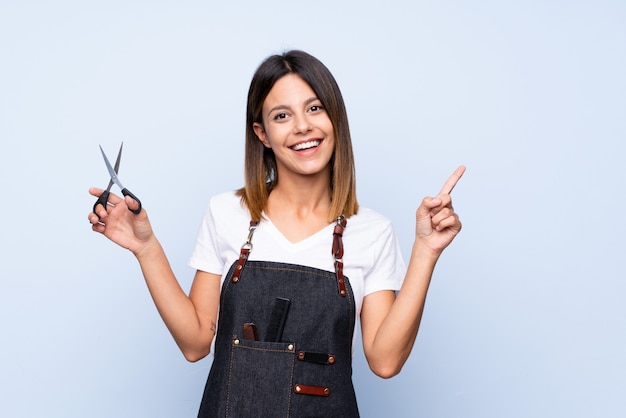 Junge Frau Uber Getrenntem Blau Mit Friseur Oder Friseurkleid Und Dem Zeigen Der Seite Premium Foto