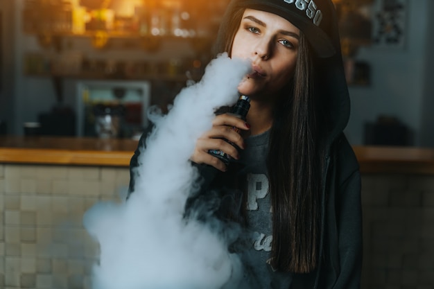 Junge Hubsche Frau In Der Mutze Rauchen Eine Elektronische Zigarette Am Vape Laden Hip Hop Stil Nahansicht Premium Foto