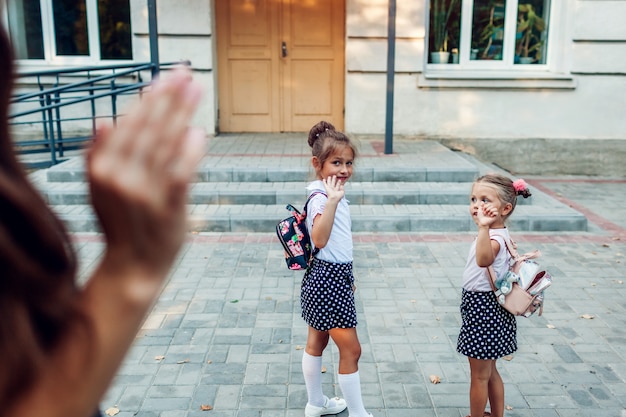 Junge mutter winkt ihren töchtern zu, bevor sie draußen in der grundschule unterrichtet und sie abschaut. Premium Fotos