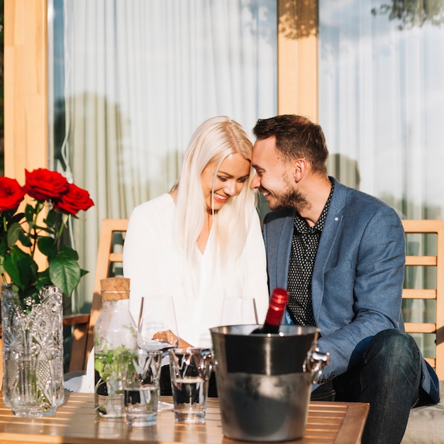 Junge Romantische Paare Die Hinter Der Tabelle Mit Weinflasche Im Eiseimer Sitzen Kostenlose Foto