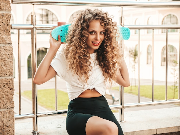 Junge Schone Sexy Lachelnde Hipster Frau Mit Afro Locken Frisur Trendiges Madchen In Sommerkleidung Positive Frau Mit Blauem Penny Skateboard Das Auf Dem Strassenhintergrund Sitzt Kostenlose Foto