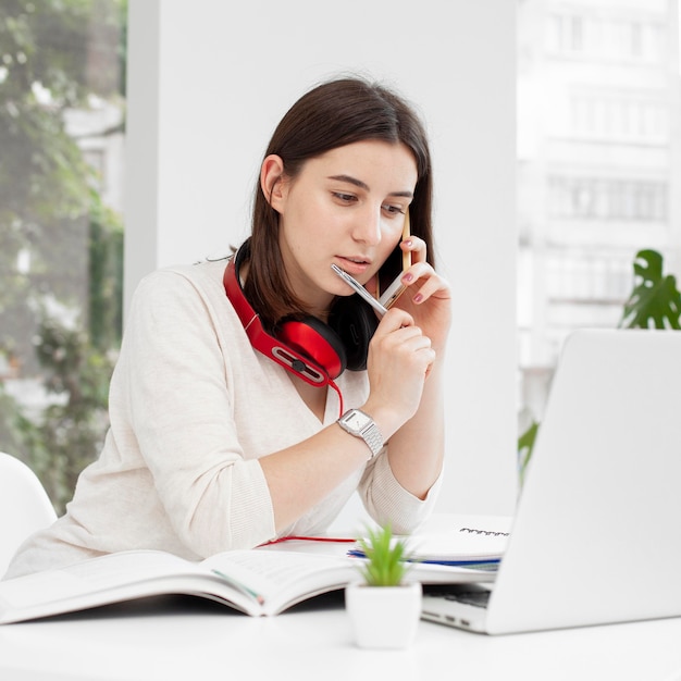 Junge tutorin zu hause mit ihrem handy und laptop