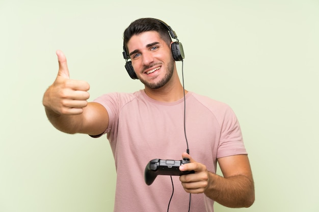 Junger gutaussehender mann, der mit einem videospielcontroller über lokalisierter grüner wand spielt Premium Fotos