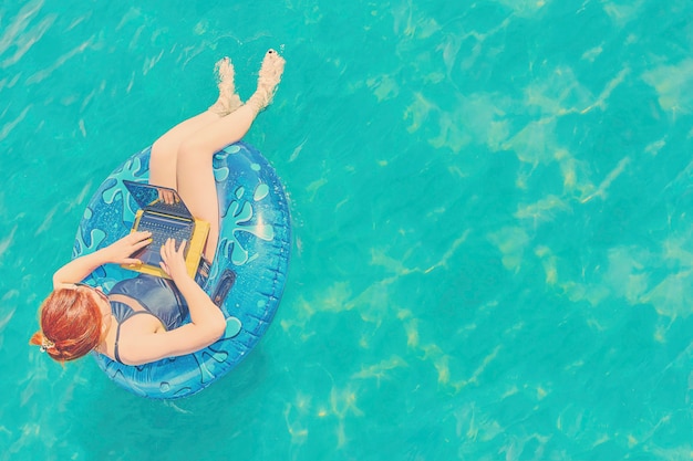 Junger hübscher frauenfreiberufler schwimmt auf dem meer oder im pool in einem schwimmenkreis Premium Fotos