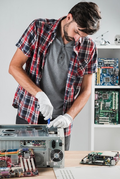 Junger männlicher techniker, der an computer-cpu in der werkstatt arbeitet Kostenlose Fotos