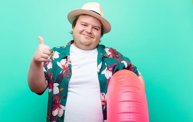 Junger mann der großen größe mit einer flachen wand des aufblasbaren donuts Premium Fotos