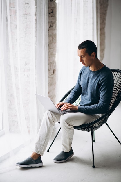 Junger Mann Der Im Stuhl Sitzt Und Laptop Verwendet Kostenlose Foto 