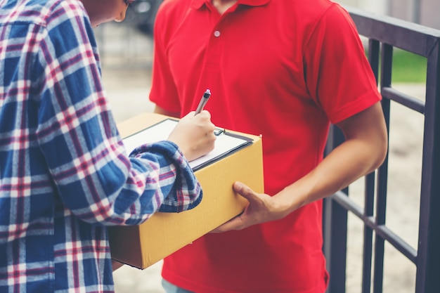 Junger mann, der paket an kunden zu hause liefert