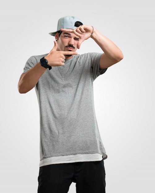 Junger rapper-mann, der eine rahmenform mit den händen macht und versucht, sich zu konzentrieren, als ob es eine kamera wäre Premium Fotos