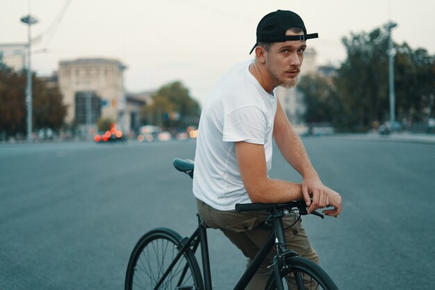 Junger schöner mann, der beim sitzen auf dem fahrrad