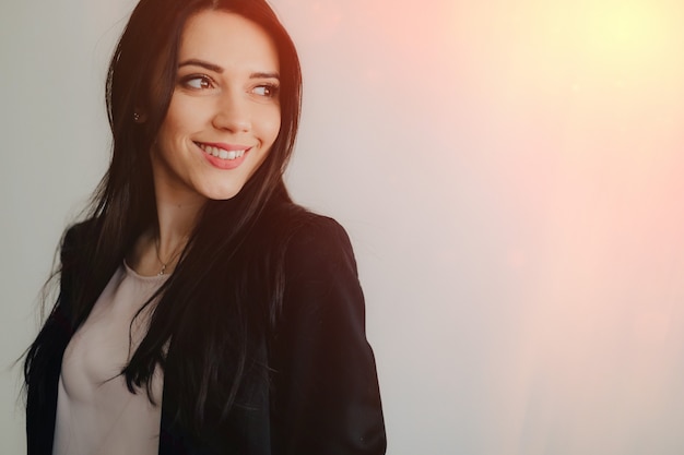 Junges attraktives emotionales mädchen in der geschäftart kleidung auf einem normalen weißen hintergrund in einem büro oder in einem publikum Premium Fotos