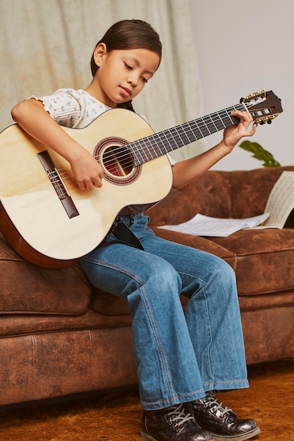 Junges mädchen lernt, wie man zu hause gitarre spielt ...