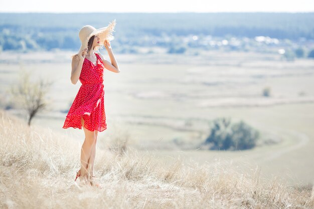 Junges schönheitsporträt draußen auf saftigem sommer oder herbst frau auf abfallzeit. dame auf der natur, die rotes stilvolles kleid trägt. Premium Fotos