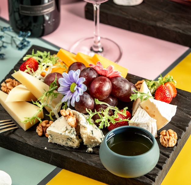 Kaseplatte Mit Cheddar Ziege Gouda Blauschimmelkase Honig Trauben Und Blumen Kostenlose Foto