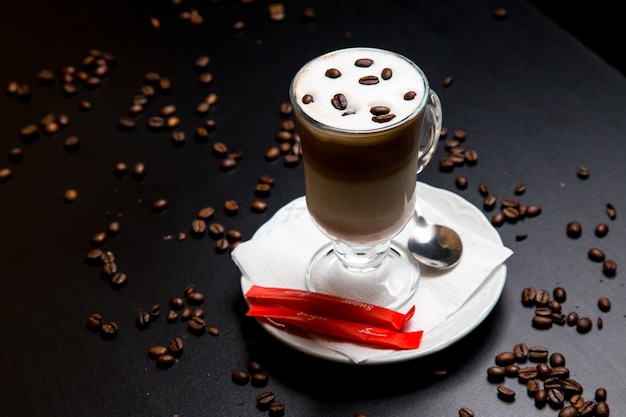 Kaffee latte auf dem tisch mit bohnen zuckerlöffel seitenansicht ...