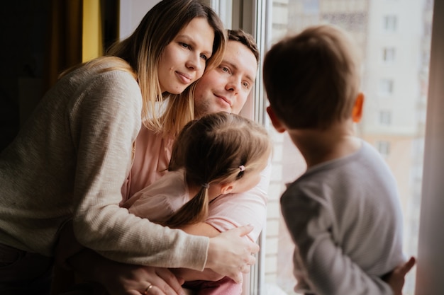 Kaukasische familie, die aus dem fenster schaut, bleibt