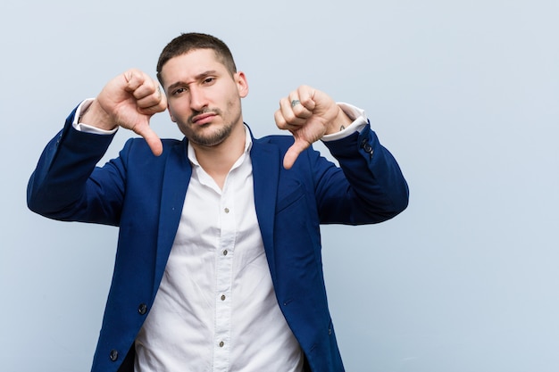 Kaukasischer mann des jungen geschäfts, der unten daumen zeigt und abneigung ausdrückt Premium Fotos
