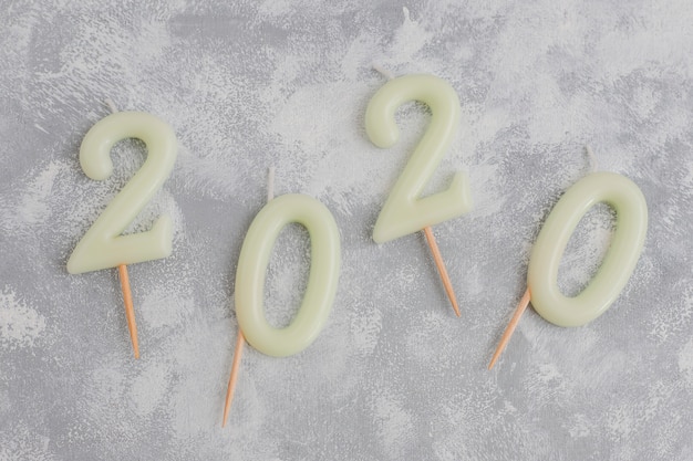 Kerzen in form von nr. 2020 als symbol des neuen jahres nahe bei weihnachten formten scheinbonbons auf einer grauen tabelle. draufsicht, flach zu legen Kostenlose Fotos