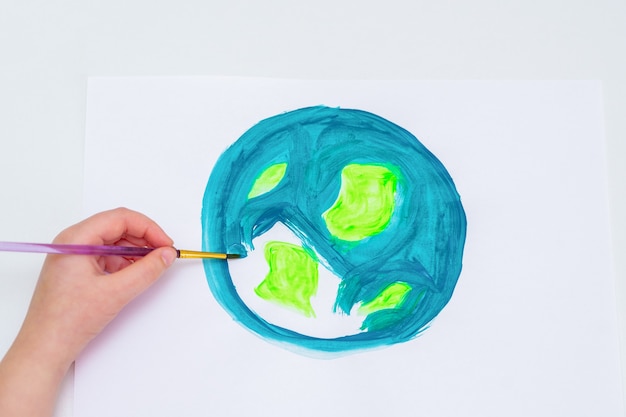 Kinderhand, die einen planeten erde mit einer weltkarte mit aquarellen