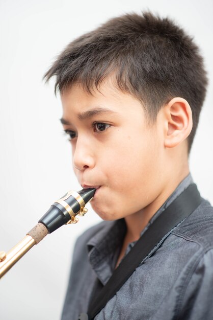Kleiner asiatischer musikerjunge, der saxophon spielt Premium Fotos