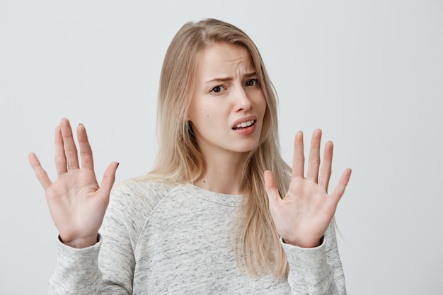 Kostenlose Foto Korpersprache Gestresste Frau Die Ihr Blondes Haar Locker An Der Grauen Wand Posiert Die Hande In Der Stopp Geste Halt Und Versucht Sich Zu Verteidigen Als Ob Sie Sagt Hor