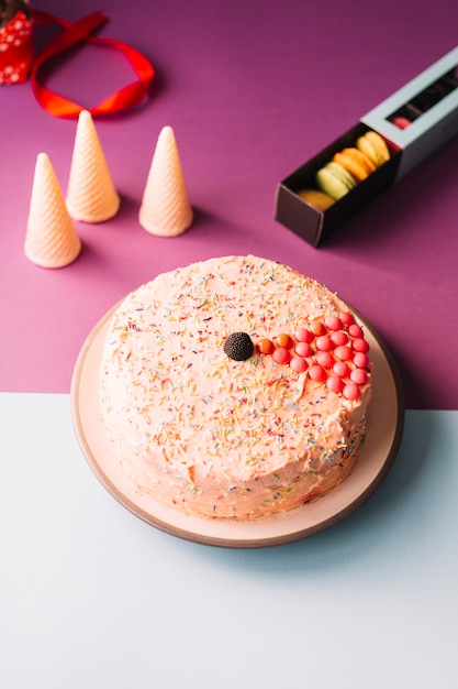 Köstlicher kuchen mit waffelkegeln und -makronen auf rosa ...