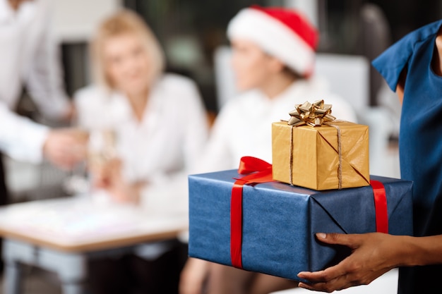 Kollegen feiern weihnachtsfeier im büro lächelnd geschenke geben