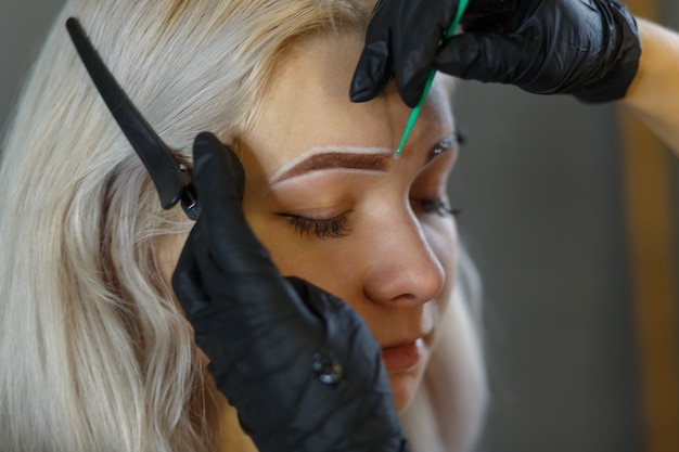 Kosmetikerin trägt permanent makeup auf augenbrauen auf augenbrauen