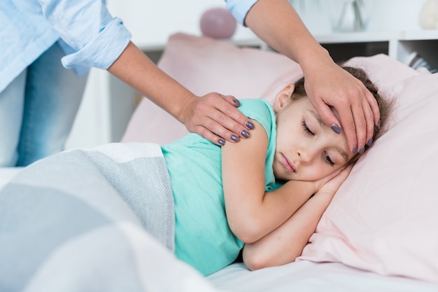 Krankes Kleines Madchen Das Im Bett Unter Der Decke Liegt Wahrend Ihre Mutter Die Stirn Beruhrt Um Zu Sehen Ob Die Temperatur Hoch Ist Premium Foto