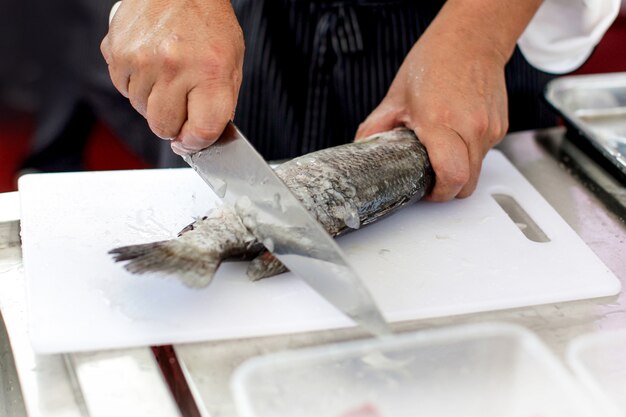 Küchenchef bei der arbeit, küchenchef beim filetieren von fischen in der küche, küchenchef beim filetieren von fischen in der restaurantküche Premium Fotos