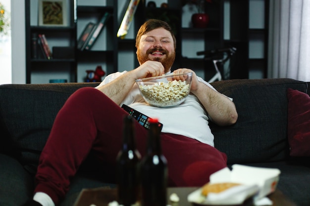 Lachender Dicker Mann Sitzt Auf Dem Sofa Isst Popcorn Und