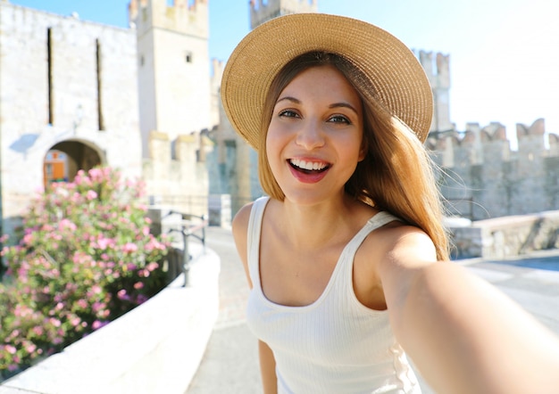 Lachelnde Junge Touristenfrau Nimmt Selbstportrat In Sirmione Italien Auf Schones Mode Madchen Macht Selfie Foto Mit Sirmione Castle Auf Dem Hintergrund Gardasee Italien Premium Foto