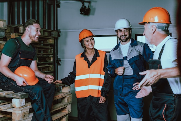 Lächelnde menschen in uniform und schutzhelmen in der pause Premium Fotos